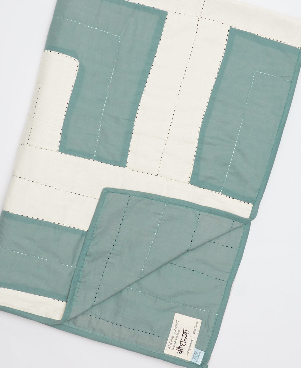 Quilt with green and white blocks on a light gray background