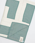 Quilt with green and white blocks on a light gray background