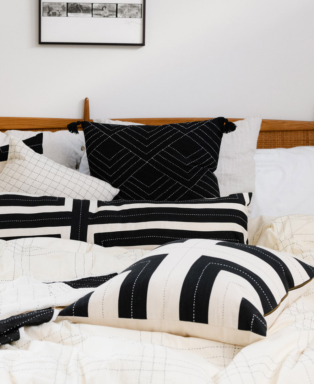 Black and white patterned pillows on a bed with a wooden headboard