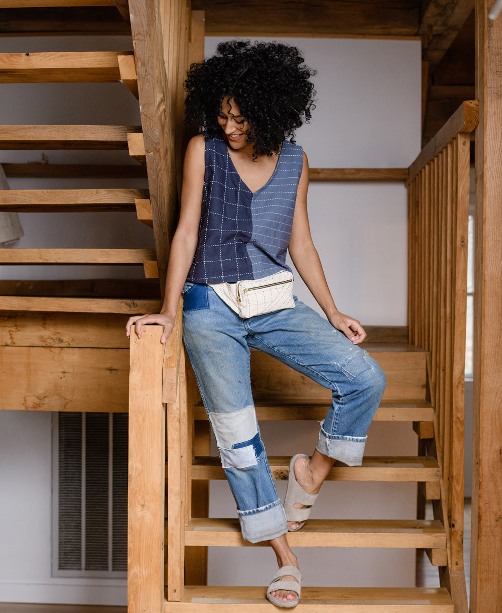 woman wearing a white belt bag around her hips standing on rustic wooden stairs