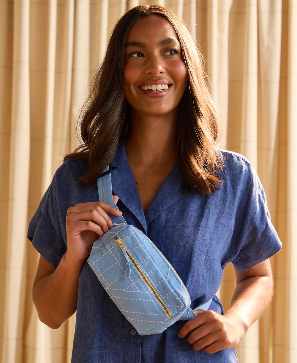 woman holding dusk blue crossbody belt bag
