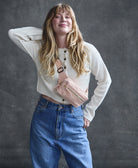 woman posing against a gray background wearing a pink crossbody belt bag