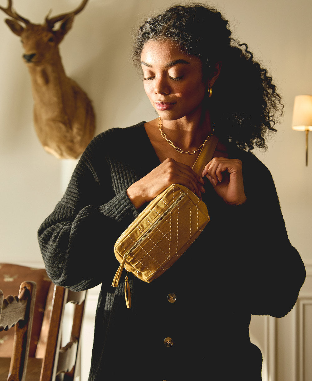 woman wearing black sweater with ochre yellow crossbody bag draped across her shoulder