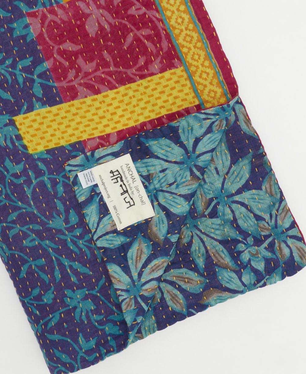 kantha quilt throw with a tag featuring the hand-stitched signature of the maker
