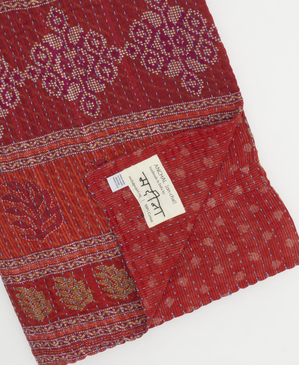 kantha quilt throw with a tag featuring the hand-stitched signature of the maker
