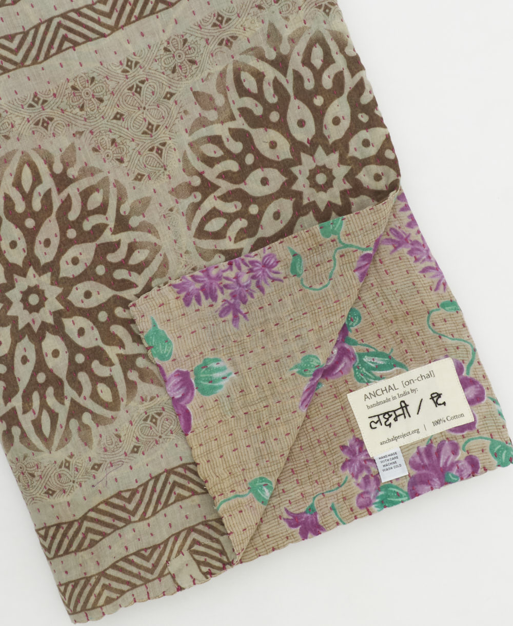 kantha quilt throw with a tag featuring the hand-stitched signature of the maker