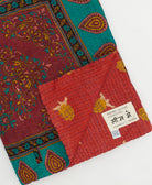 kantha quilt throw with a tag featuring the hand-stitched signature of the maker
