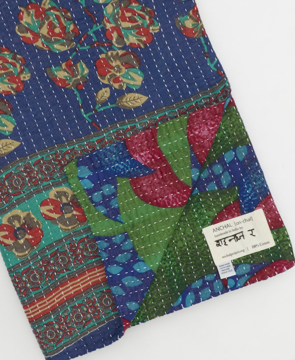 kantha quilt throw with a tag featuring the hand-stitched signature of the maker