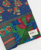 kantha quilt throw with a tag featuring the hand-stitched signature of the maker