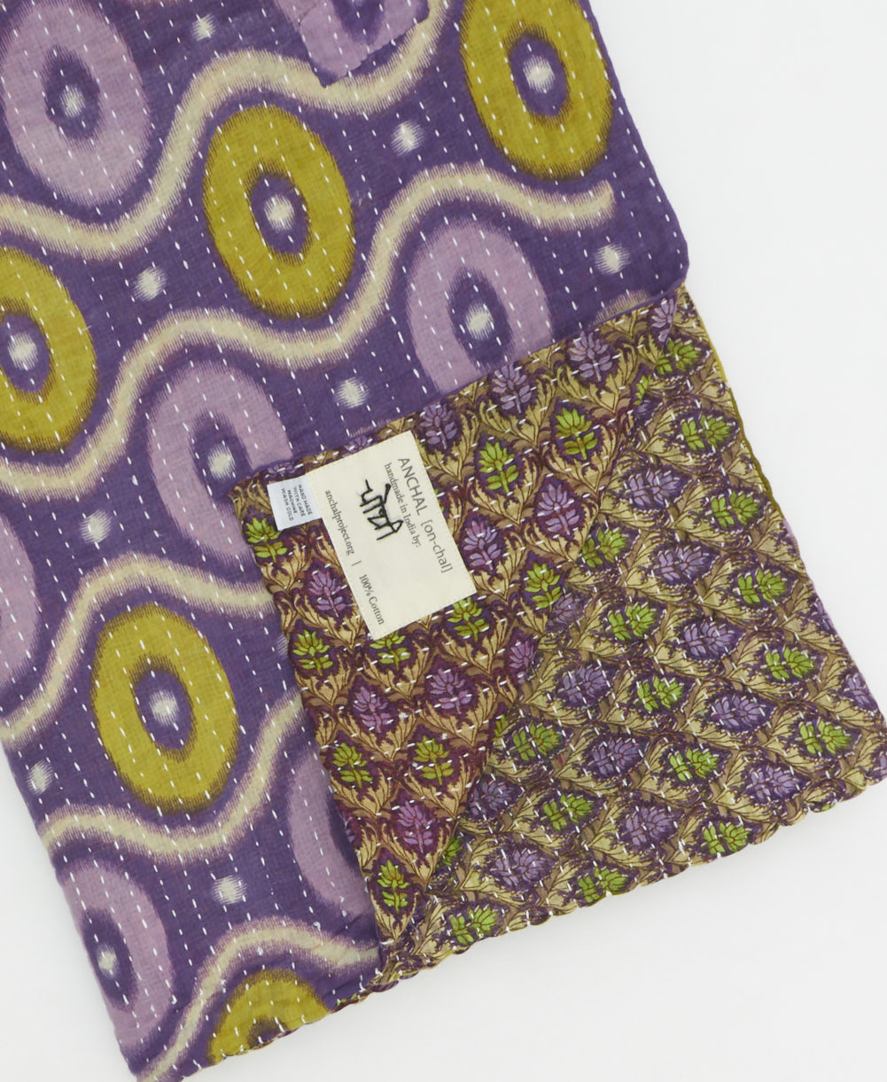 kantha quilt throw with a tag featuring the hand-stitched signature of the maker