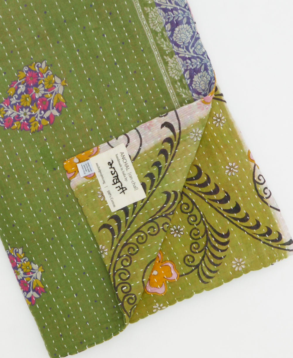 kantha quilt throw with a tag featuring the hand-stitched signature of the maker