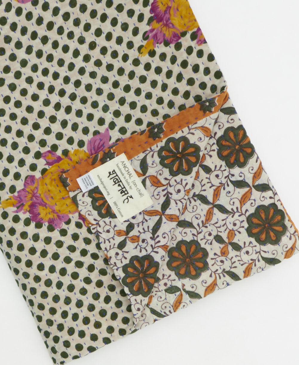 kantha quilt throw with a tag featuring the hand-stitched signature of the maker