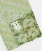 kantha quilt throw with a tag featuring the hand-stitched signature of the maker