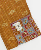 kantha quilt throw with a tag featuring the hand-stitched signature of the maker