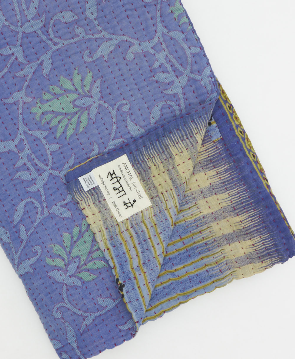 kantha quilt throw with a tag featuring the hand-stitched signature of the maker