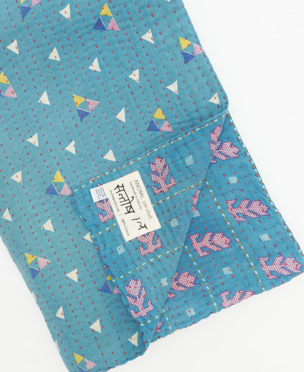 kantha quilt throw with a tag featuring the hand-stitched signature of the maker