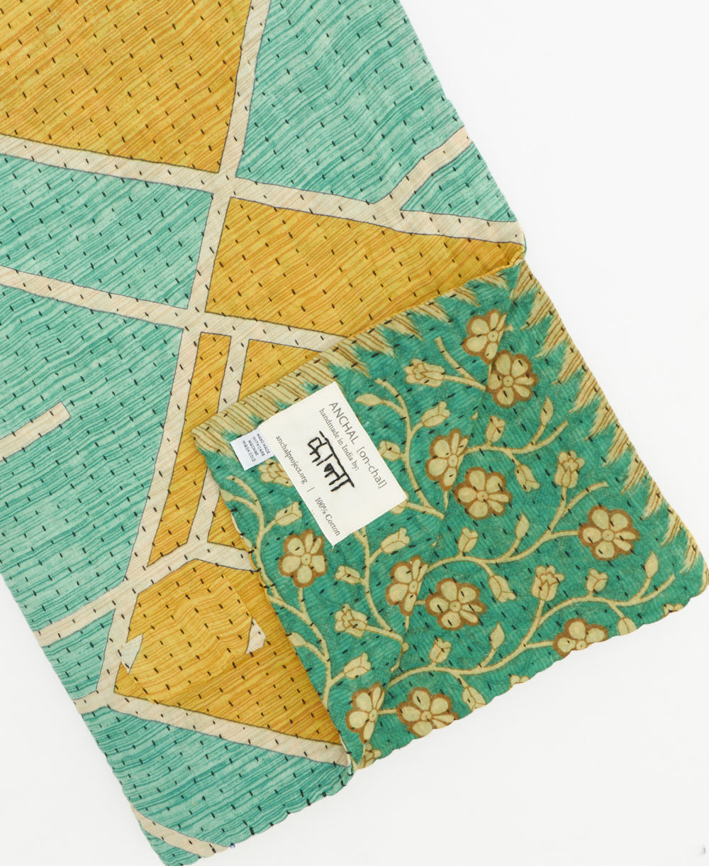 kantha quilt throw with a tag featuring the hand-stitched signature of the maker