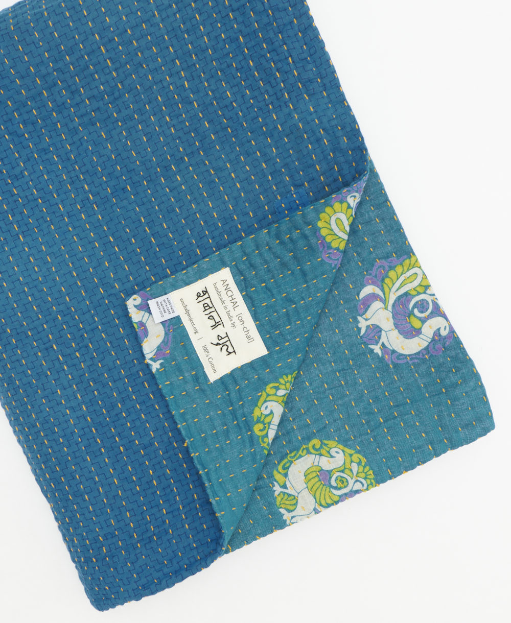 kantha quilt throw with a tag featuring the hand-stitched signature of the maker