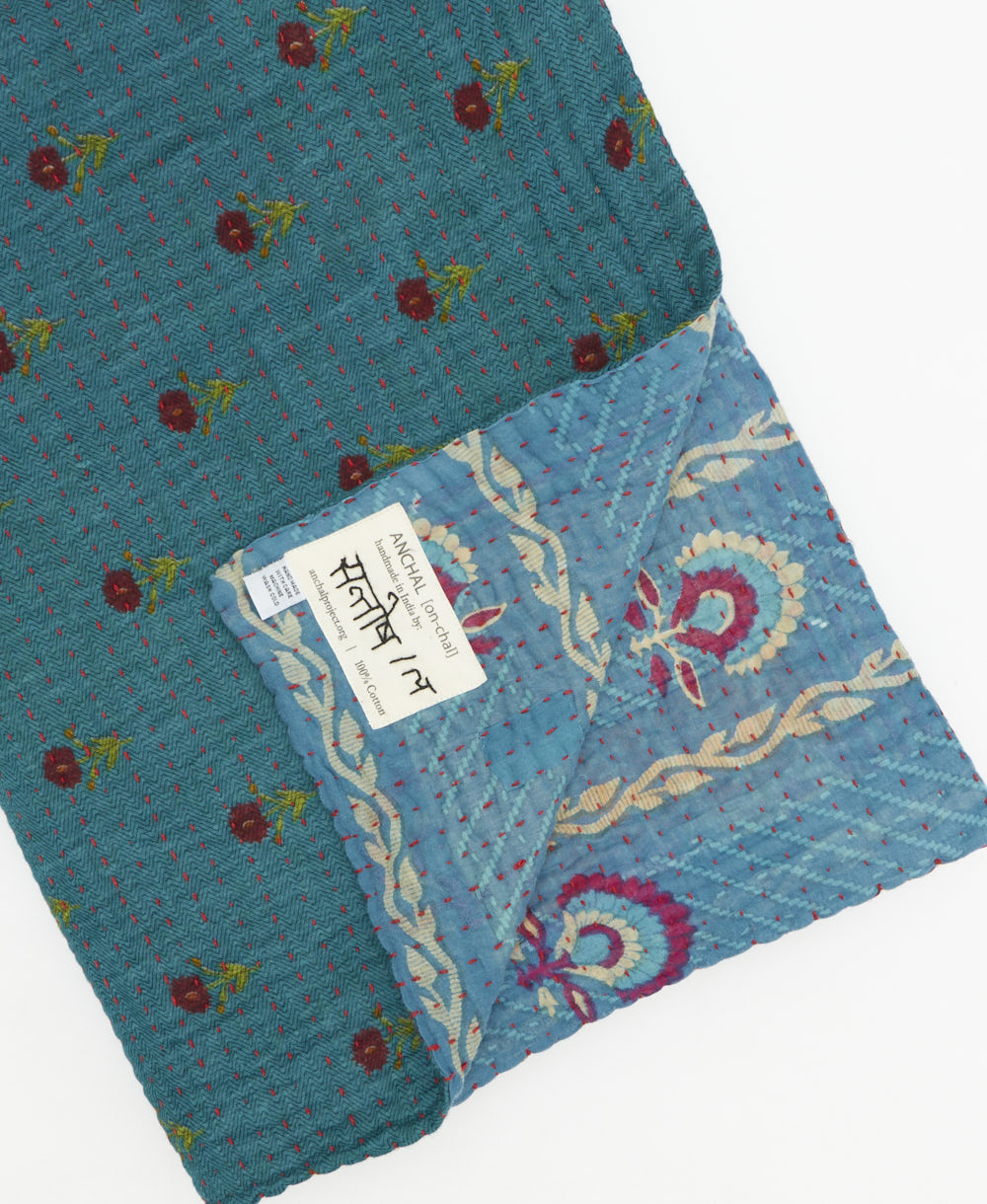 kantha quilt throw with a tag featuring the hand-stitched signature of the maker