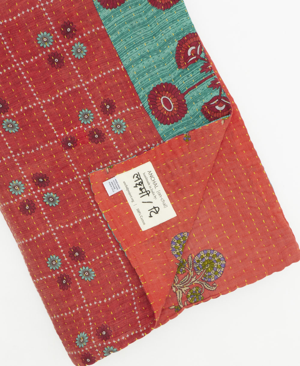 kantha quilt throw with a tag featuring the hand-stitched signature of the maker