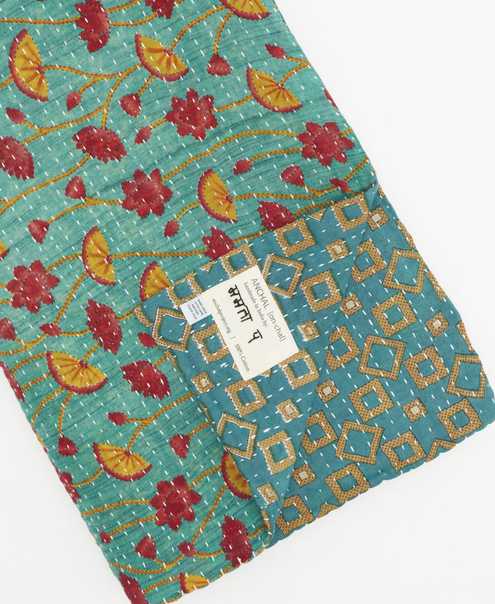 kantha quilt throw with a tag featuring the hand-stitched signature of the maker