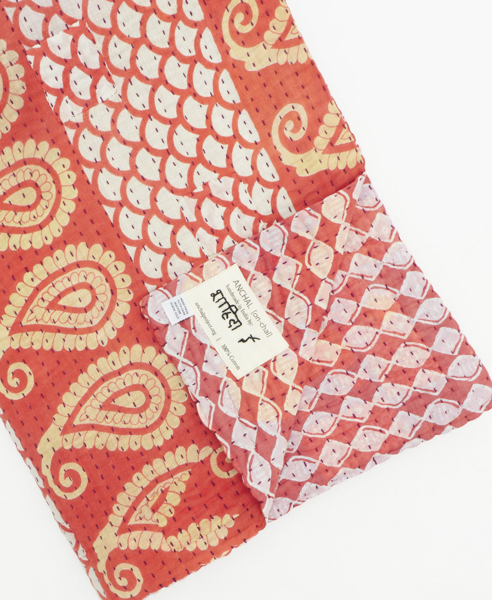 kantha quilt throw with a tag featuring the hand-stitched signature of the maker