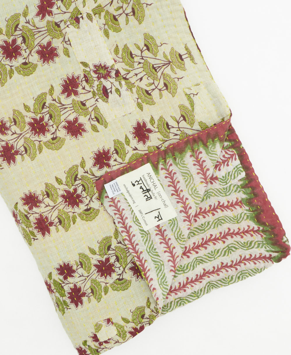 kantha quilt throw with a tag featuring the hand-stitched signature of the maker