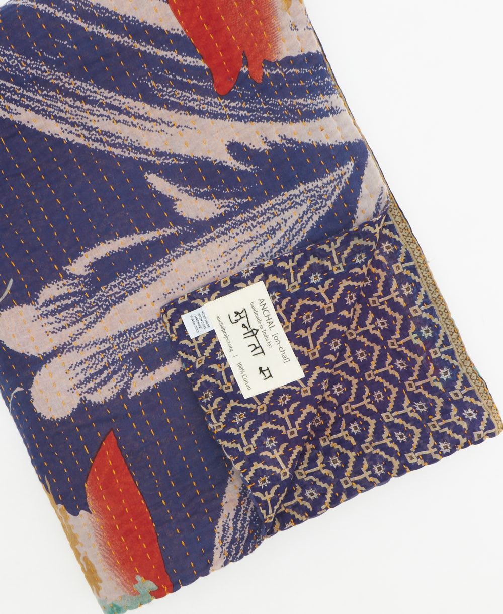 kantha quilt throw with a tag featuring the hand-stitched signature of the maker