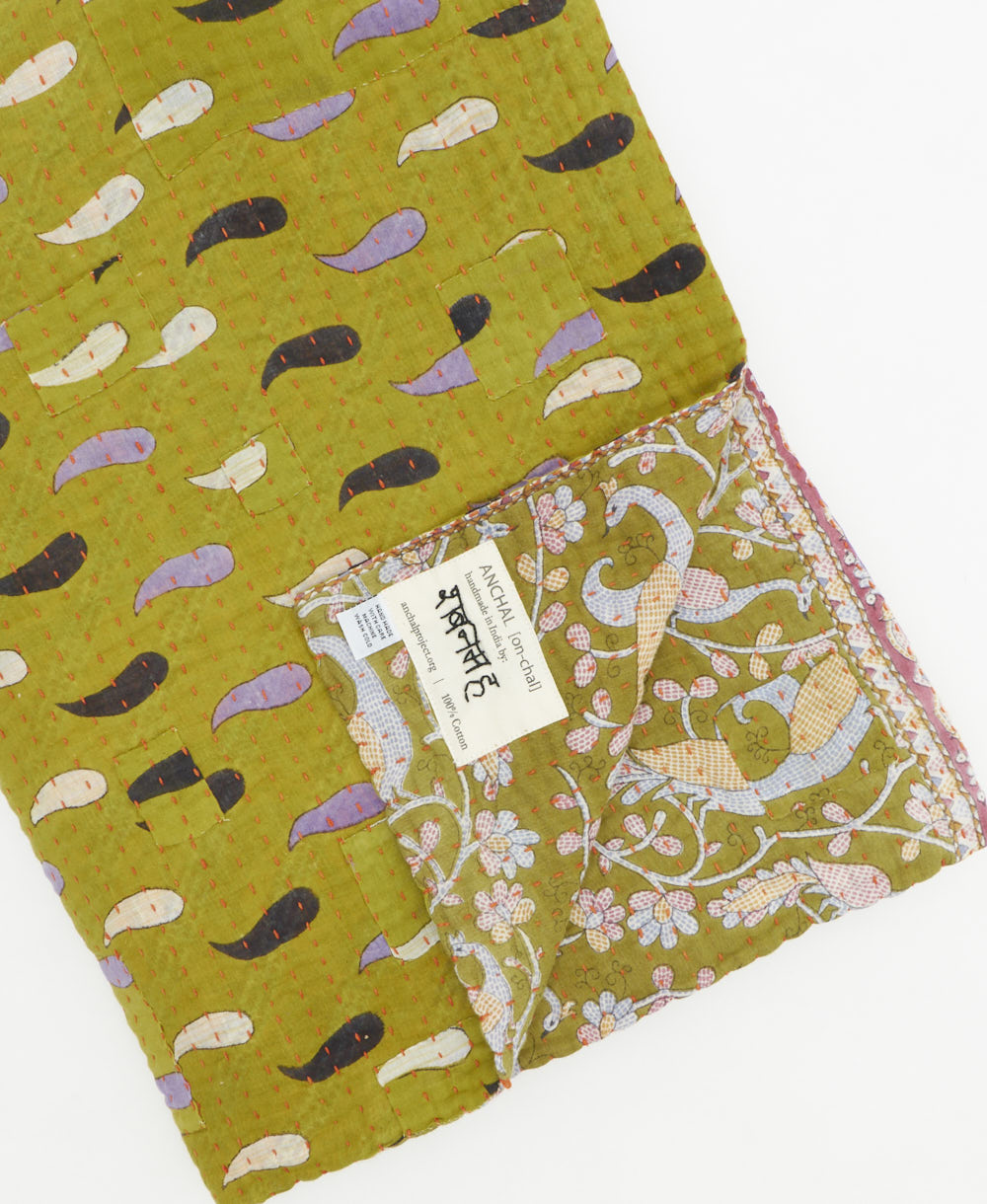 kantha quilt throw with a tag featuring the hand-stitched signature of the maker