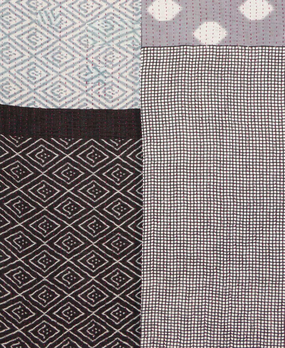 kantha quilt throw with a tag featuring the hand-stitched signature of the maker