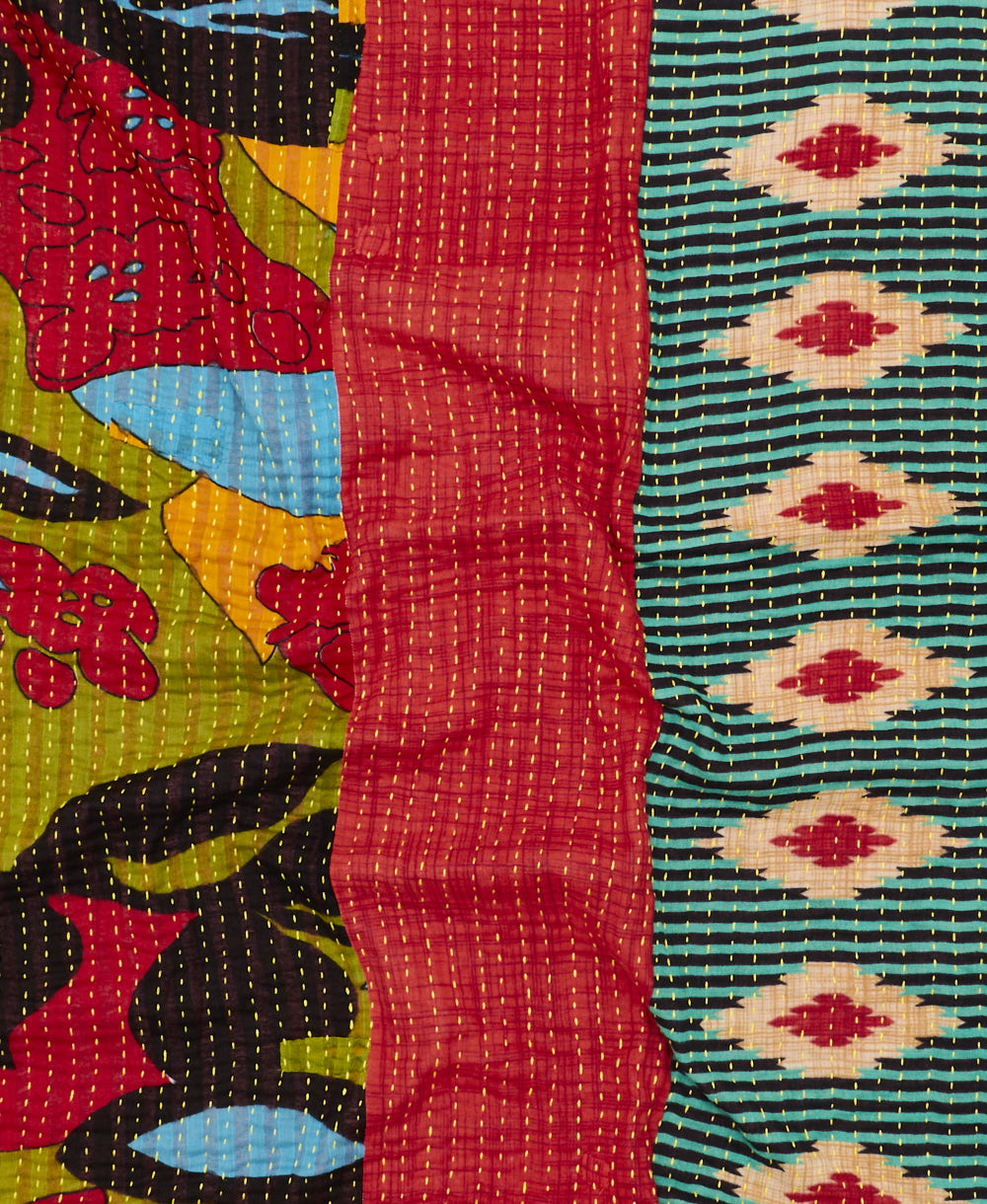 kantha quilt throw with a tag featuring the hand-stitched signature of the maker