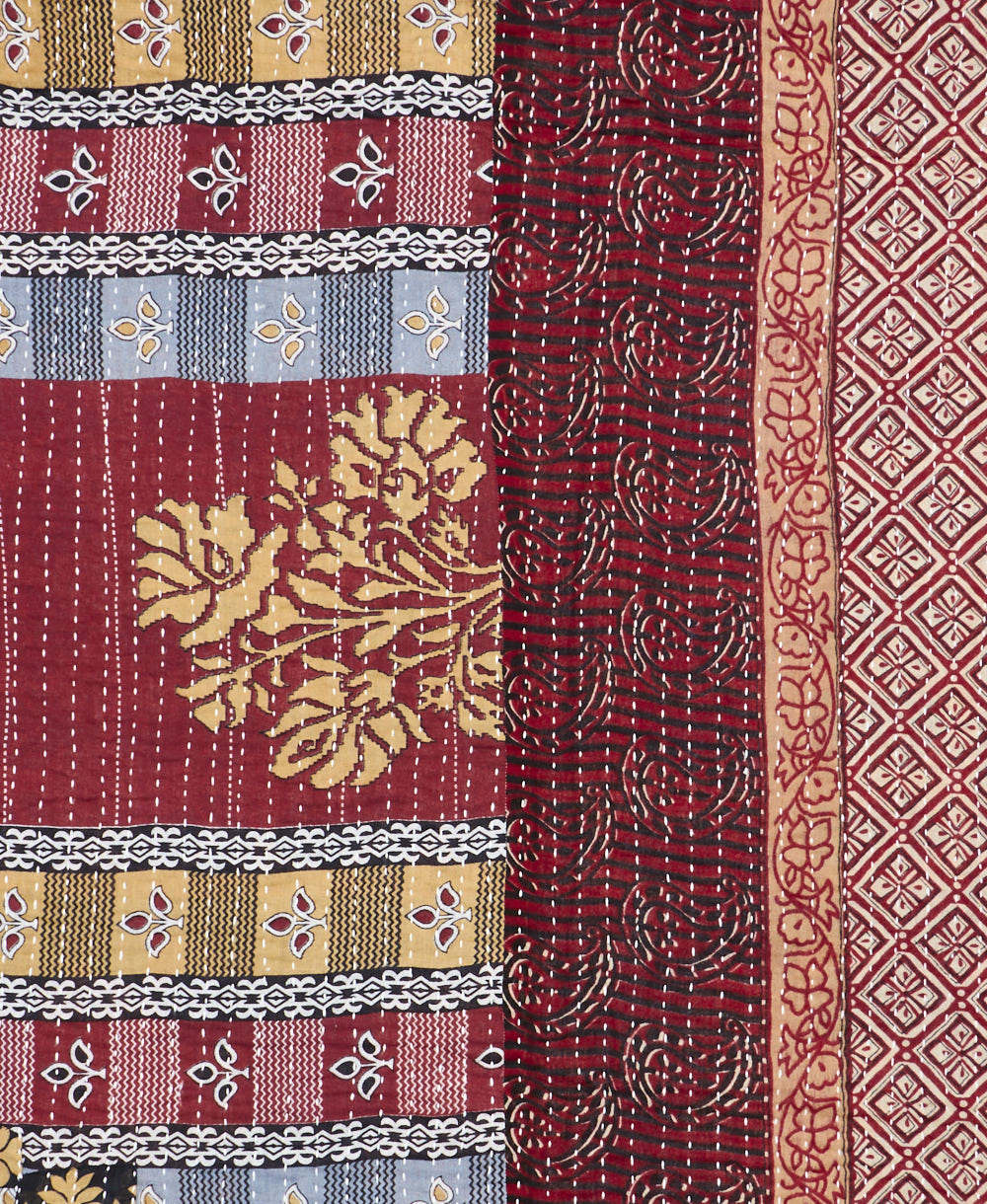 kantha quilt throw with a tag featuring the hand-stitched signature of the maker