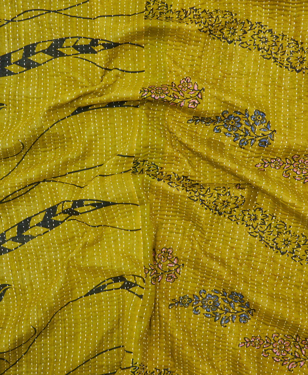 kantha quilt throw with a tag featuring the hand-stitched signature of the maker