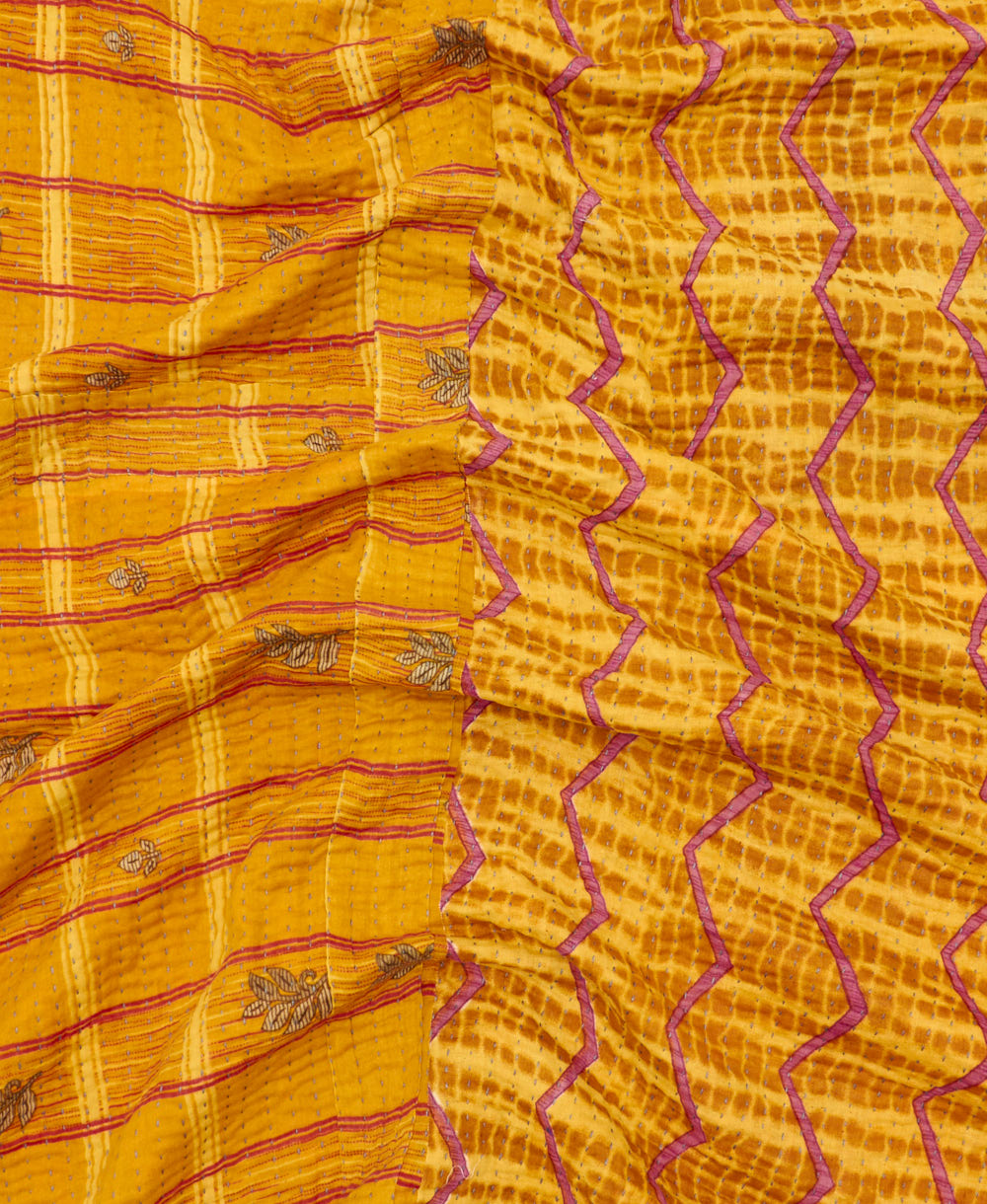 kantha quilt throw with a tag featuring the hand-stitched signature of the maker