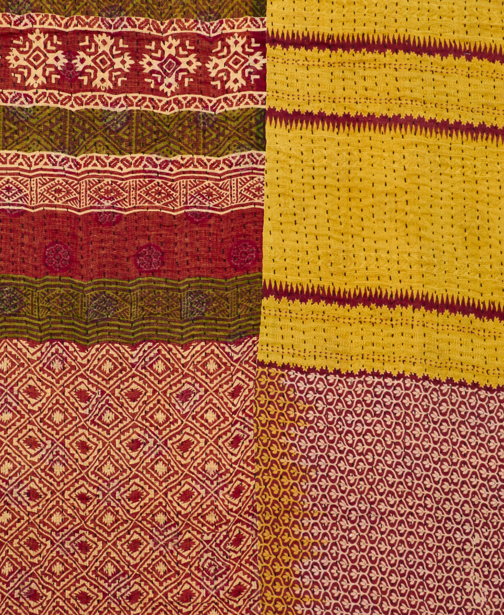 kantha quilt throw with a tag featuring the hand-stitched signature of the maker
