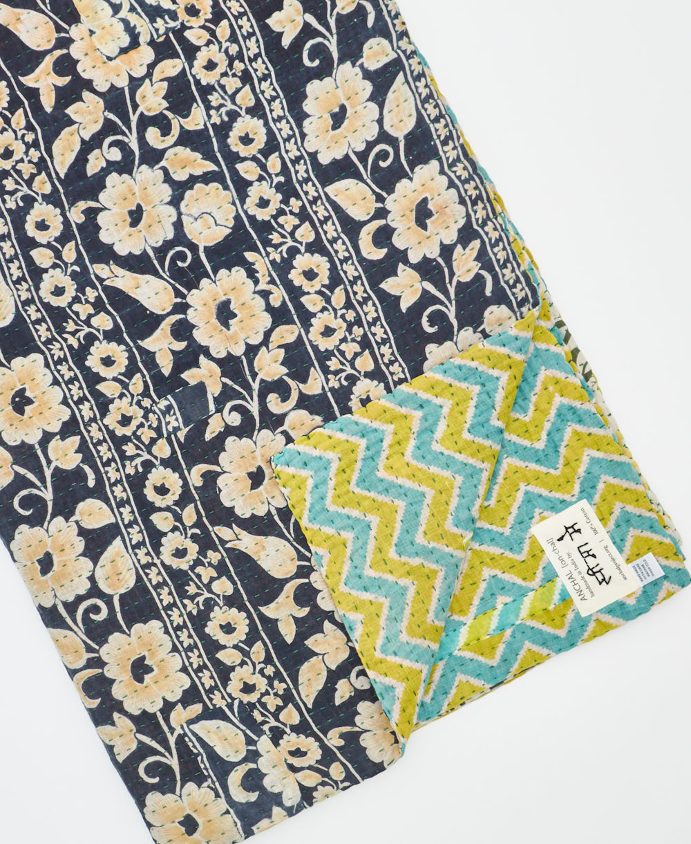 kantha quilt throw with a tag featuring the hand-stitched signature of the maker