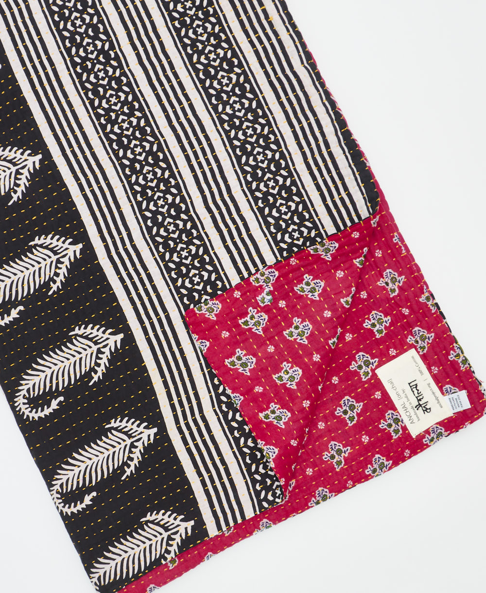 kantha quilt throw with a tag featuring the hand-stitched signature of the maker