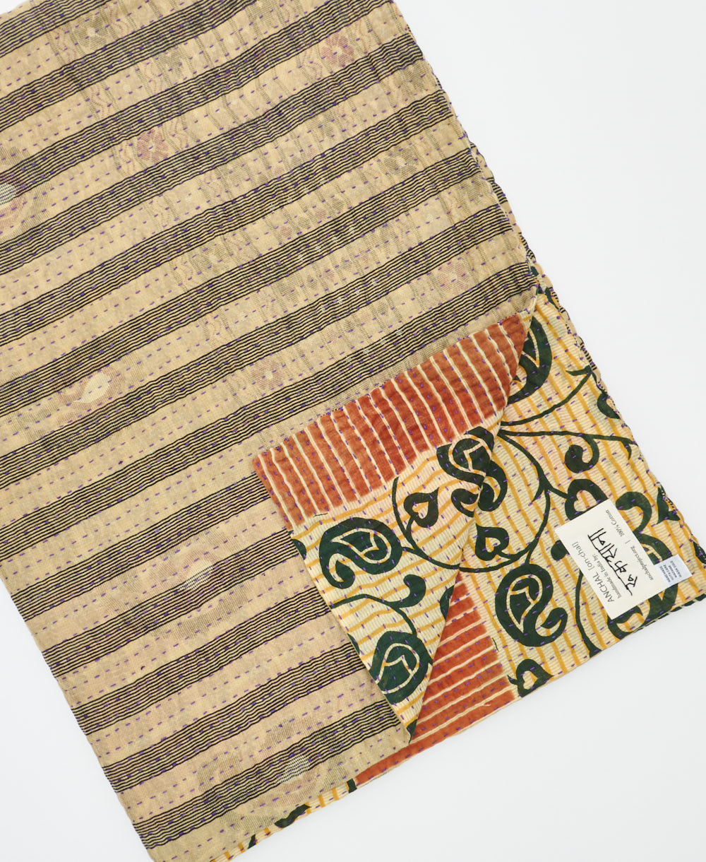 kantha quilt throw with a tag featuring the hand-stitched signature of the maker