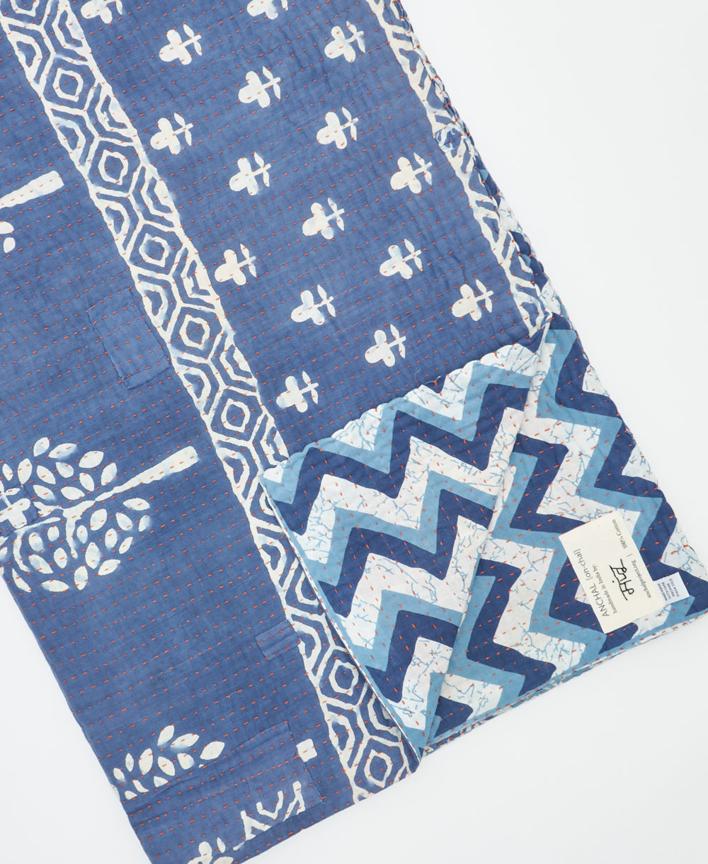 kantha quilt throw with a tag featuring the hand-stitched signature of the maker