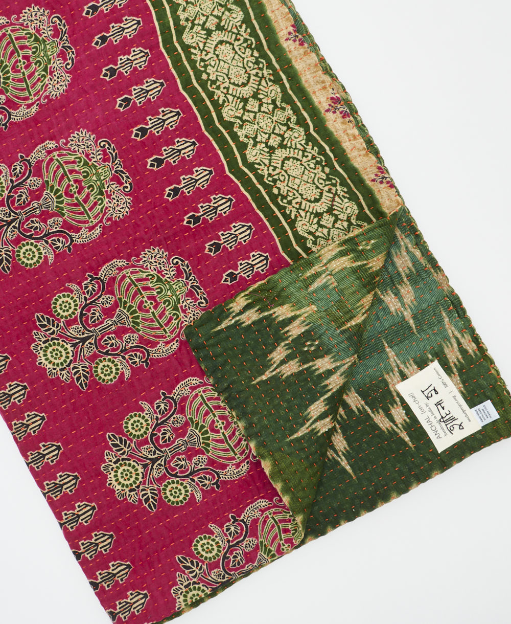 kantha quilt throw with a tag featuring the hand-stitched signature of the maker
