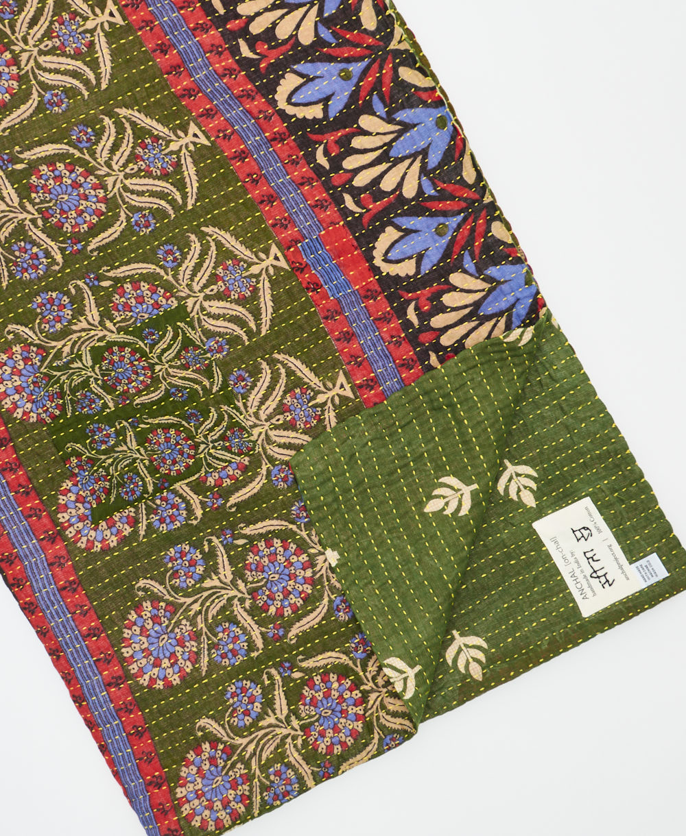 kantha quilt throw with a tag featuring the hand-stitched signature of the maker