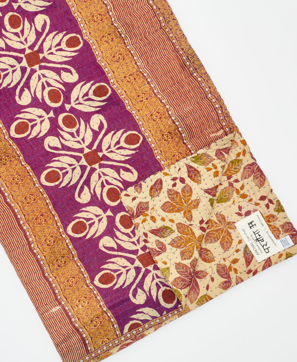 kantha quilt throw with a tag featuring the hand-stitched signature of the maker