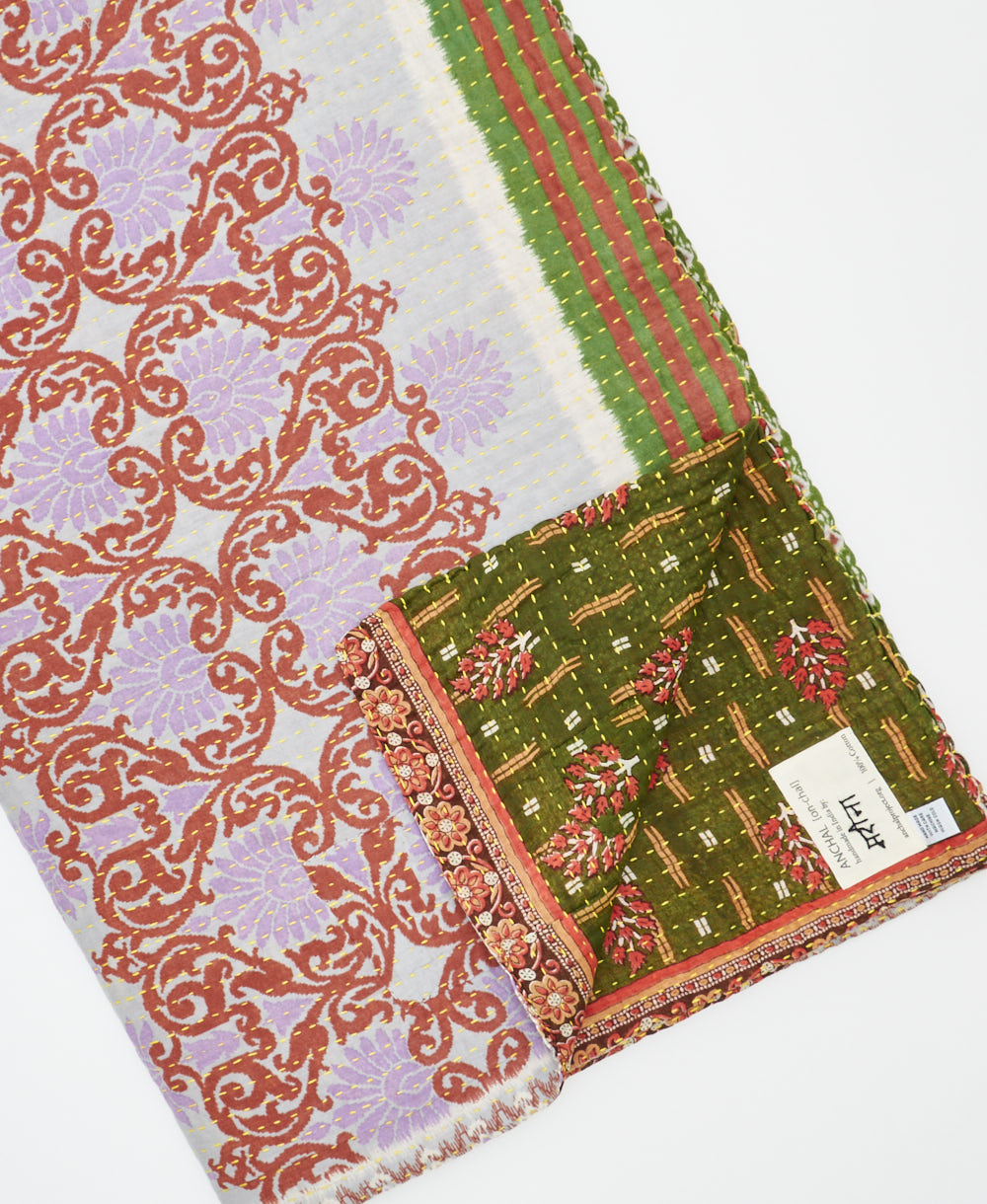 kantha quilt throw with a tag featuring the hand-stitched signature of the maker