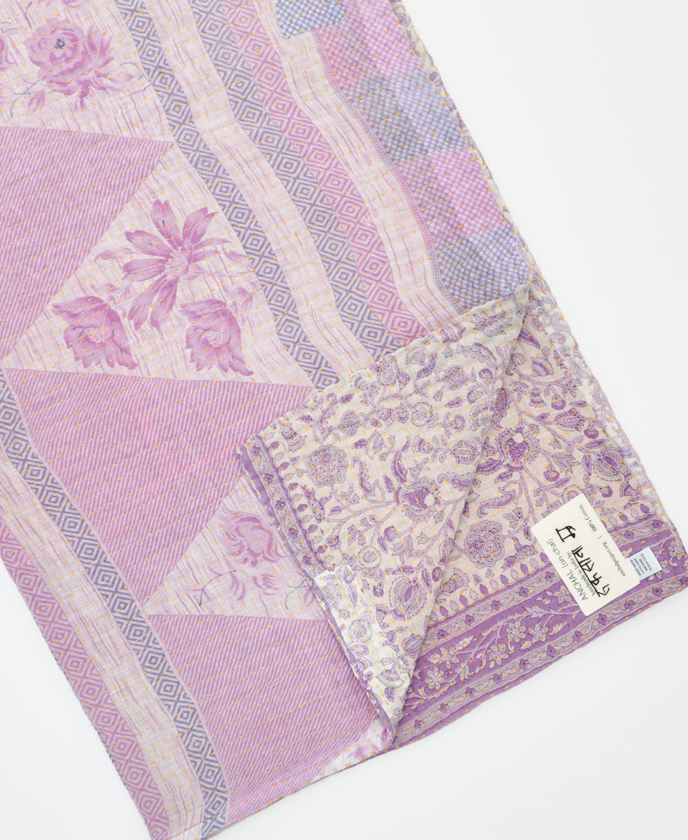 kantha quilt throw with a tag featuring the hand-stitched signature of the maker
