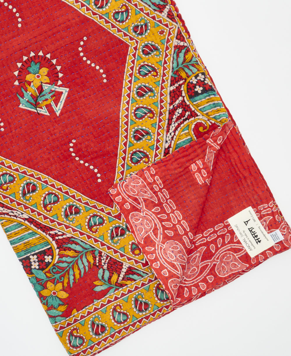 kantha quilt throw with a tag featuring the hand-stitched signature of the maker