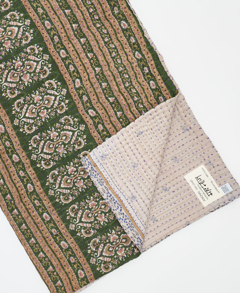 kantha quilt throw with a tag featuring the hand-stitched signature of the maker