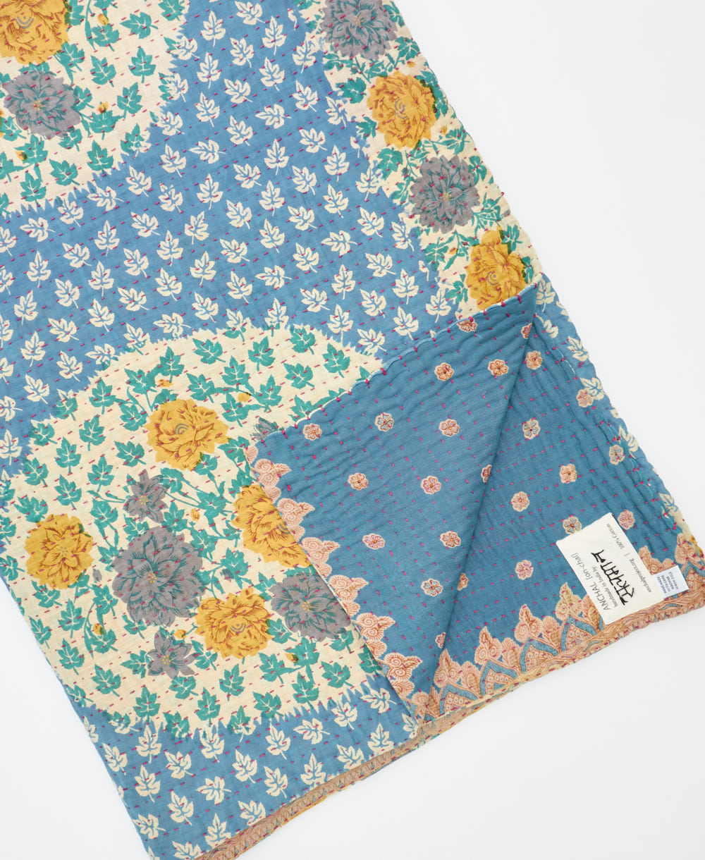 kantha quilt throw with a tag featuring the hand-stitched signature of the maker