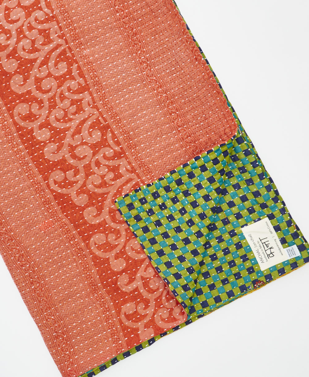 kantha quilt throw with a tag featuring the hand-stitched signature of the maker