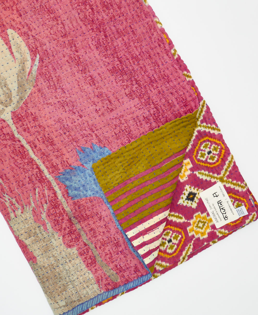 kantha quilt throw with a tag featuring the hand-stitched signature of the maker