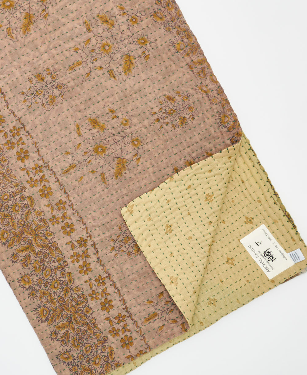 kantha quilt throw with a tag featuring the hand-stitched signature of the maker
